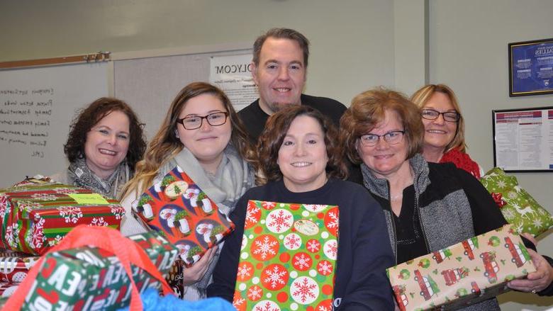 Staff members gather for a photo with wrapped gifts